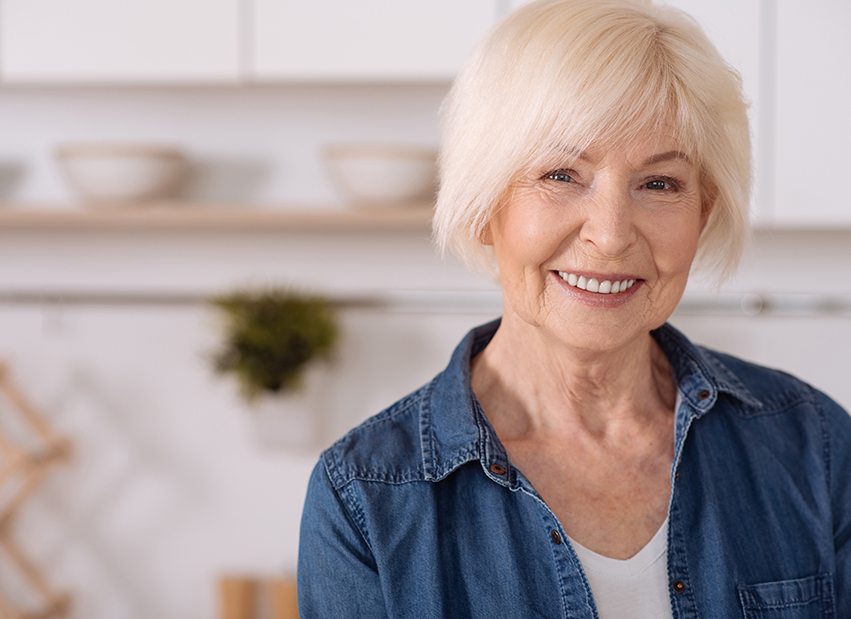 Senior woman with denim jacket smiling in kitchen