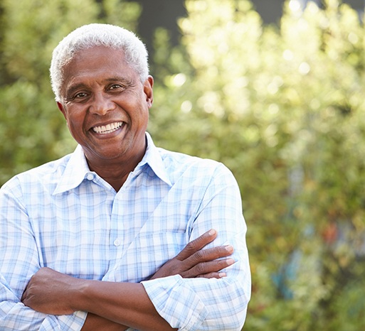 Man standing outside smiling with arms folded