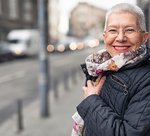 Senior woman with scarf and glasses walking down street