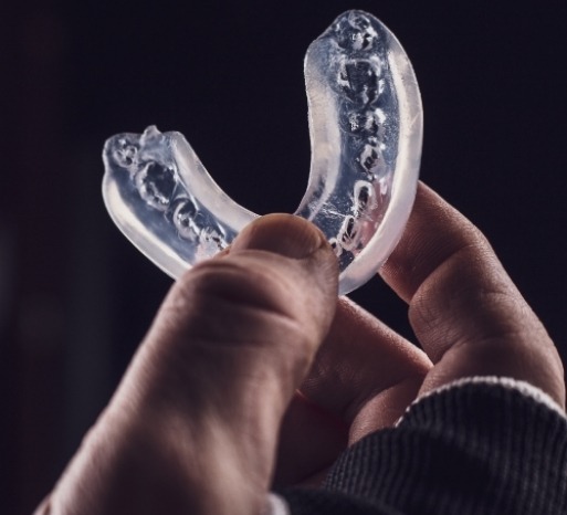 Hand holding a clear nightguard for bruxism