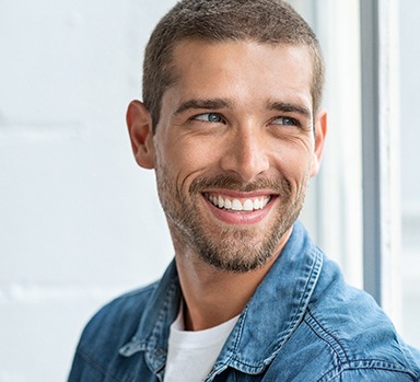 Man in denim jacket looking out window and smiling