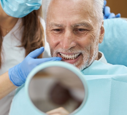 Man looking at smile after four step dental implant process