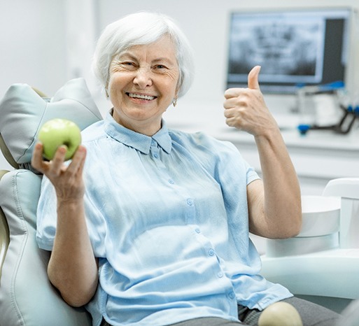 A senior woman holding a green apple