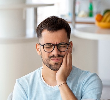 Closeup of man with glasses experiencing tooth pain