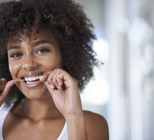 Woman flossing teeth to prevent dental emergencies