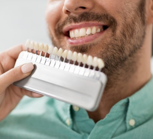 Man's smile compared with tooth shade chart after teeth whitening