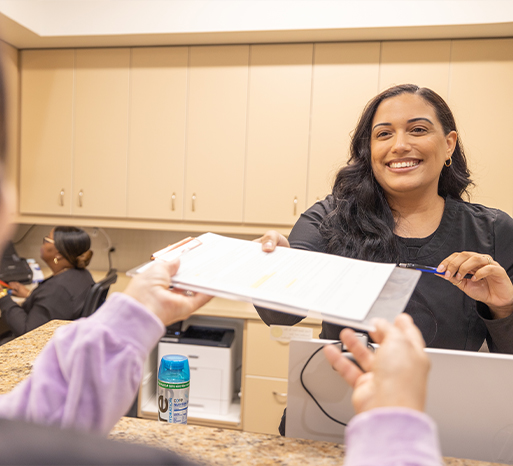 Dental team member in Itasca taking clipboard from patient at front desk