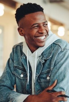 Smiling young man in denim jacket sitting at desk