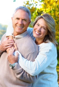 Man and woman sharing smiles after replacing missing teeth