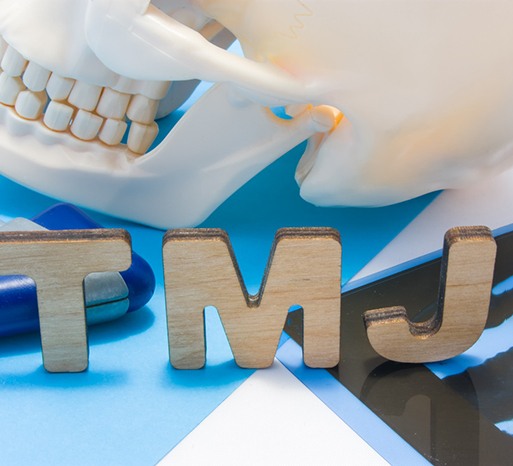 Cardboard letters spelling out TMJ next to model of skull